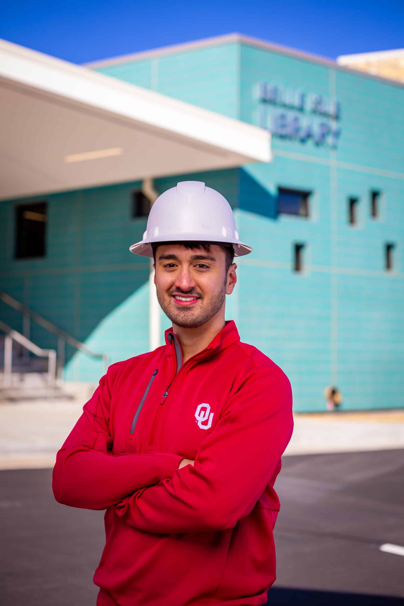 a student wearing a construction hat standing in front of a building